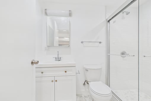 A white bathroom with a toilet, sink, and shower.