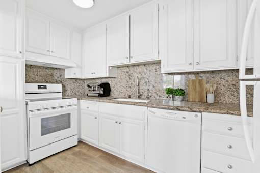 A kitchen with white cabinets and appliances.