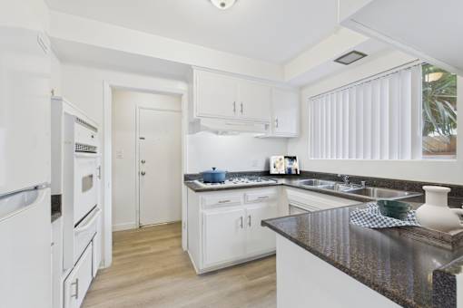 A kitchen with white cabinets and a black countertop.