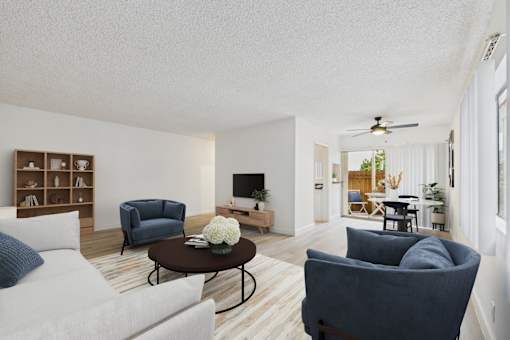 A living room with a white couch, a blue chair, and a coffee table with a flower on it.