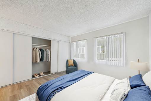 A bedroom with a bed, pillows, a chair, and a wardrobe.