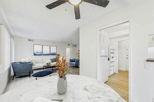 A living room with a white ceiling fan and a grey sofa.