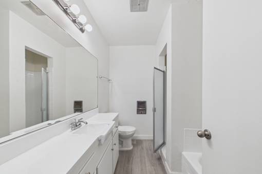 A white bathroom with a sink, toilet, and mirror.