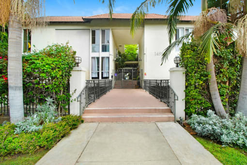 a house with palm trees and a sidewalk in front of it
