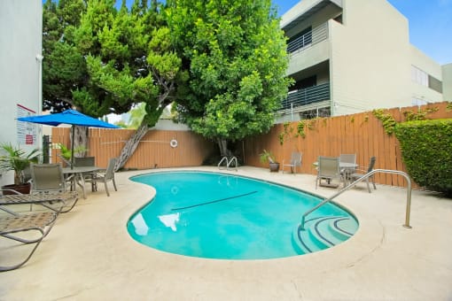 a swimming pool with chairs and umbrellas in front of a building