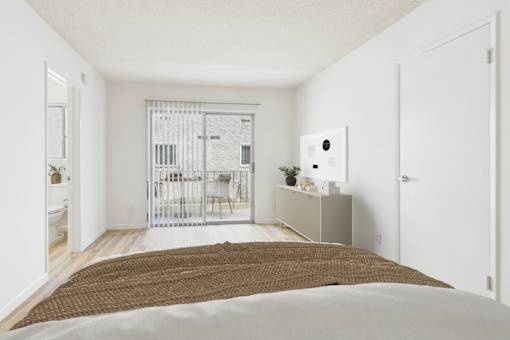 A bedroom with a bed, a cabinet, and a balcony with a gate.