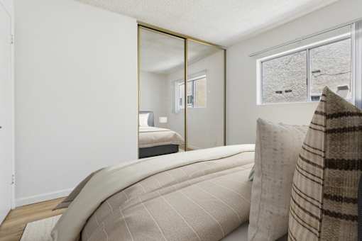 A bedroom with a large bed and a mirror on the wall.