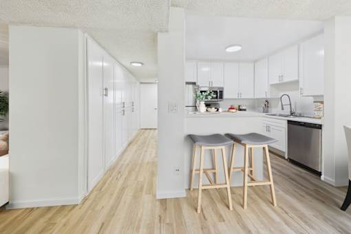 A kitchen with white cabinets and a wooden floor.