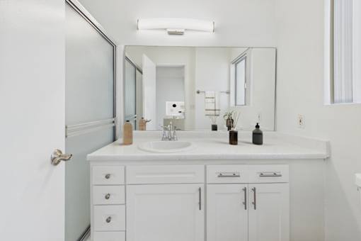 A white bathroom with a sink and mirror.
