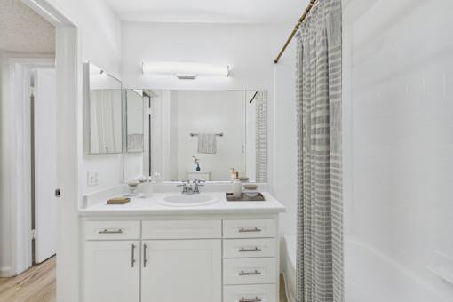 A white bathroom with a double sink and a large mirror.