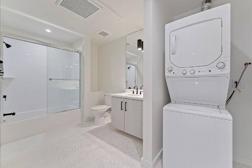 A white bathroom with a toilet, sink, and shower.