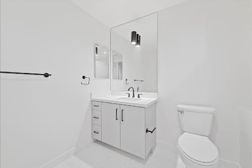 A white bathroom with a toilet, sink, and mirror.