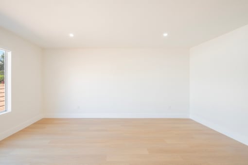 an empty room with white walls and wood floors
