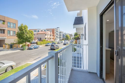 a view of a street from a balcony with a white railing