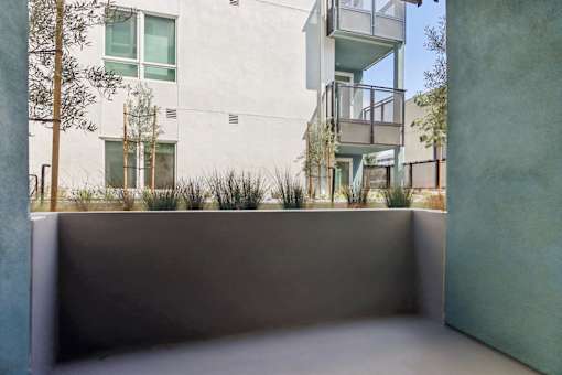 A white building with a balcony and a tree in front of it.