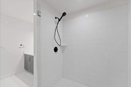 A white tiled bathroom with a shower head and hand held shower.
