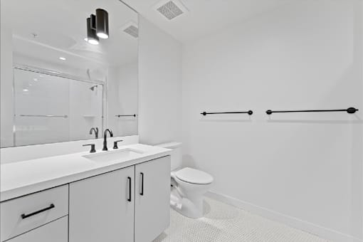 A white bathroom with a toilet, sink, and mirror.