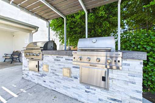 A stainless steel grill is attached to a stone wall.