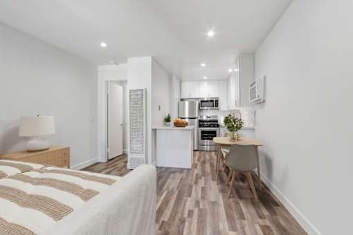 A bedroom with a bed, a chair, and a small kitchen area.