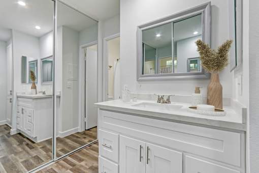 A bathroom with a vanity, sink, and mirror.
