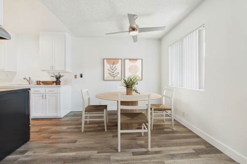 A dining room with a table set for two and a ceiling fan.