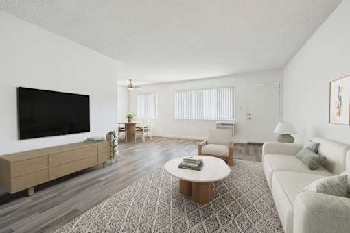 A living room with a flat screen TV, a white sofa, a wooden coffee table, and a rug.