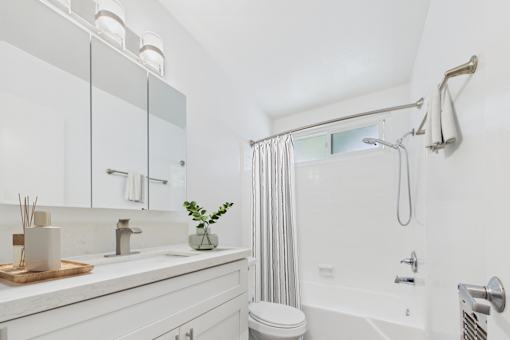 A white bathroom with a toilet, sink, and shower.