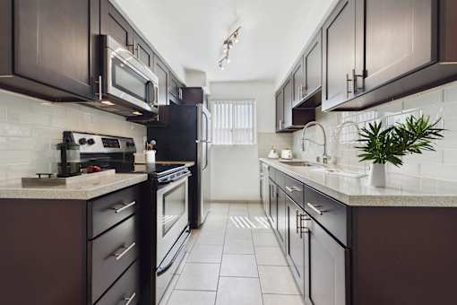 A kitchen with dark brown cabinets and white countertops.
