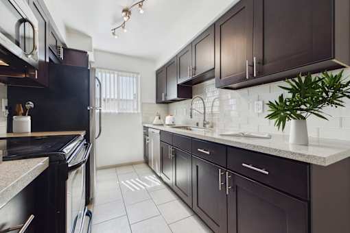 A kitchen with dark brown cabinets and a black refrigerator.