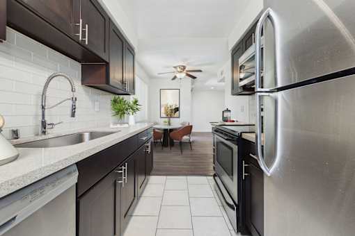 A modern kitchen with a stainless steel refrigerator and black cabinets.