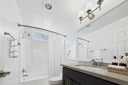 A white bathroom with a towel hanging on the shower rod.