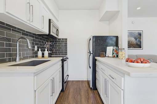 A kitchen with white cabinets and a black fridge.