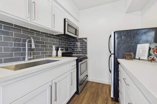 A kitchen with white cabinets and a black fridge.