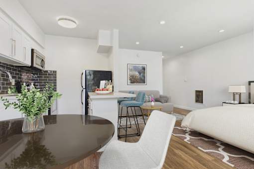 A modern kitchen with a black fridge and a dining table with a white chair.