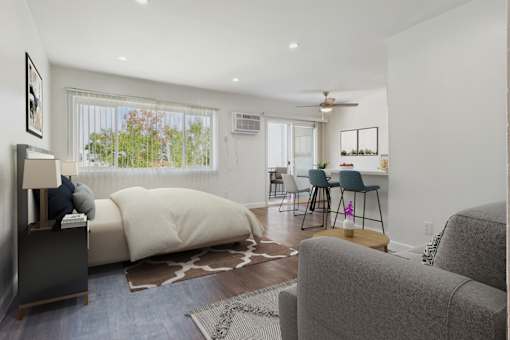 A living room with a grey couch and a white bed.