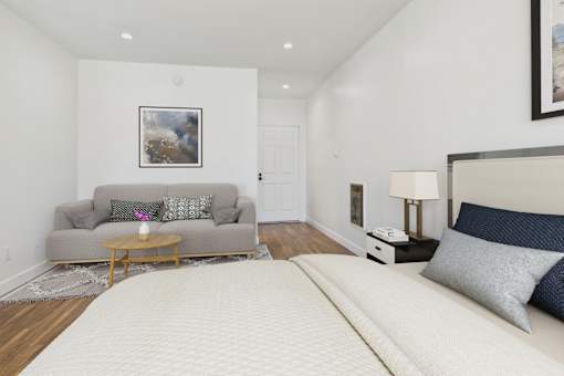 A bedroom with a large bed and a grey couch.
