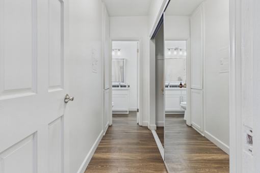 A long white hallway with a wooden floor and white walls.