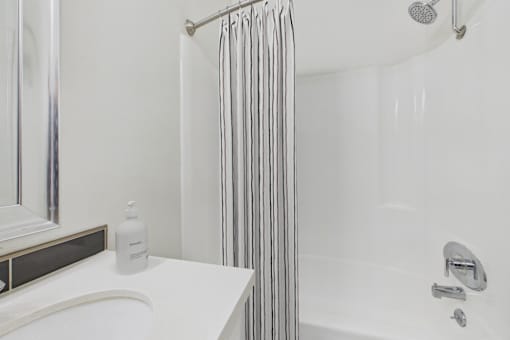 A white bathroom with a white tub and a white shower curtain.