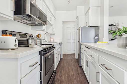 A white kitchen with a stove top oven and a refrigerator.
