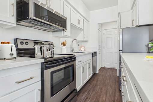 A modern kitchen with white cabinets and stainless steel appliances.