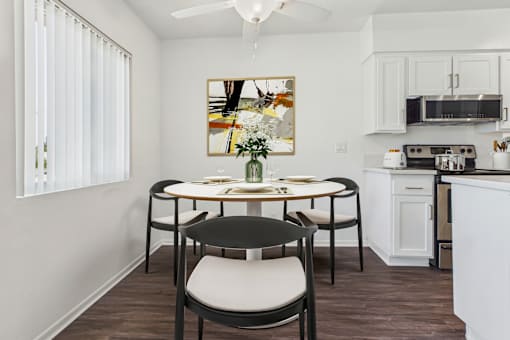 A dining room with a table set for two and a painting on the wall.