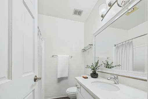A white bathroom with a toilet, sink, and mirror.