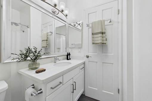 A white bathroom with a toilet, sink, and mirror.