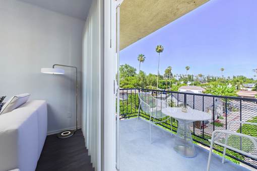 A balcony with a table and chairs overlooking a green area.