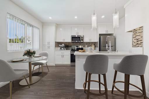 A modern kitchen with white cabinets and a bar area.