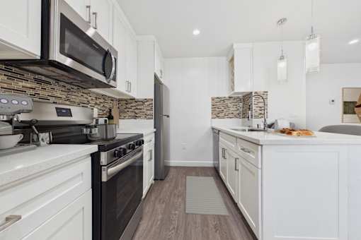 A kitchen with a black stove top oven and white cabinets.