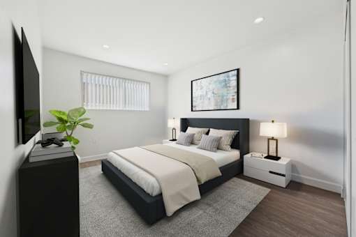 A modern bedroom with a large bed, a television, and a plant.