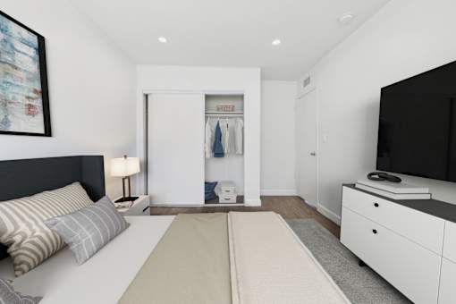 A bedroom with a bed, dresser, and a television.