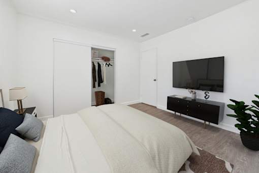 A bedroom with a large bed and a flat screen TV mounted on the wall.
