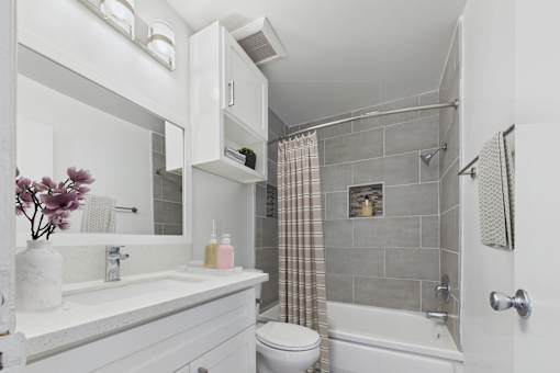 A white bathroom with a toilet, sink, and shower.